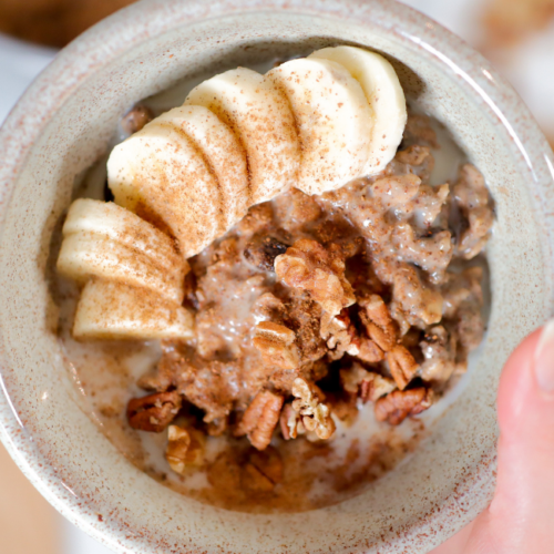 hand holding bowl of oatmeal with banana