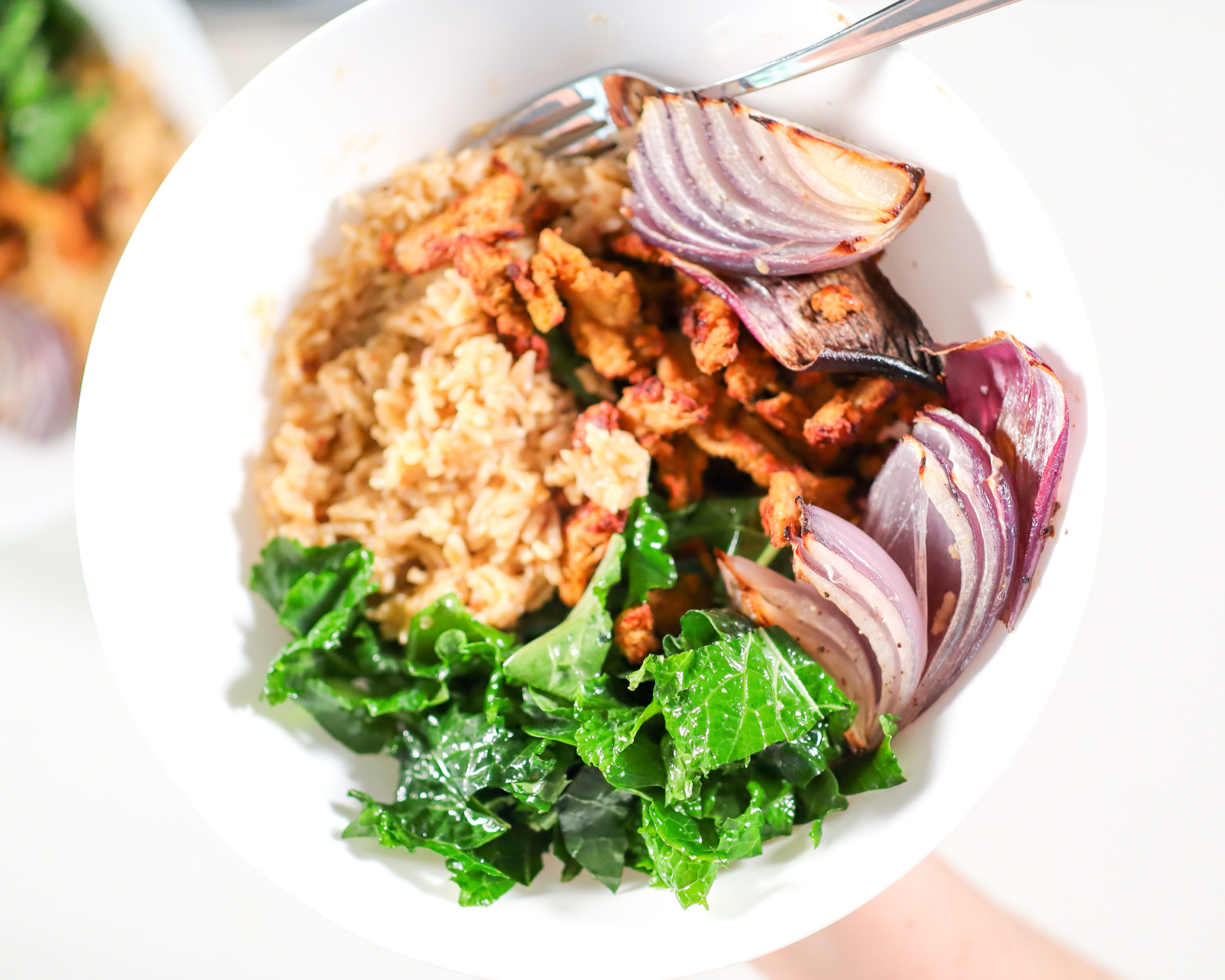 Bowl of greens, rice, soy curls and roasted red onion.