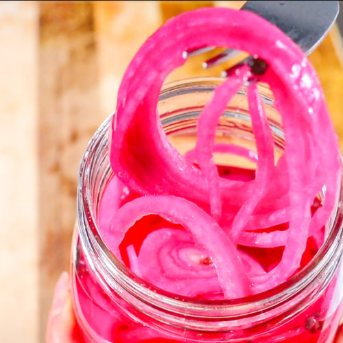 close up shot of sliced pickled red onions on a fork