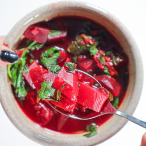 Hand holding a bowl of beet soup