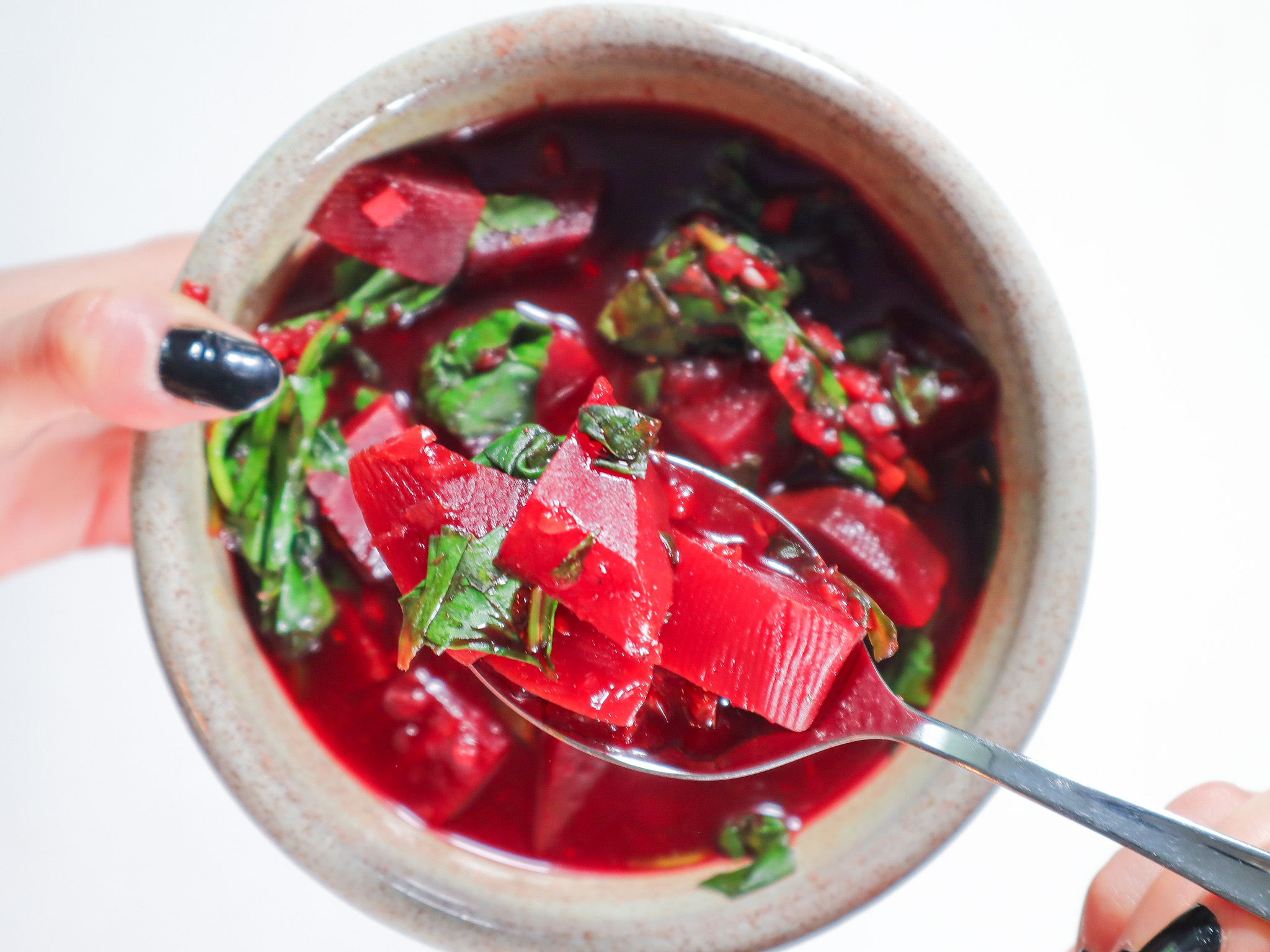 Hand holding a bowl of beet soup