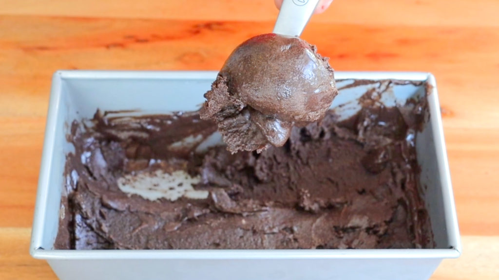 Scooping chocolate ice cream out of a container