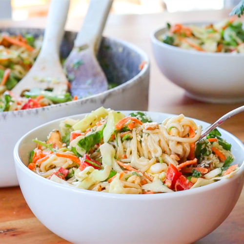 Hand holding a forkful of delicious Crunchy Cashew Noodle Salad