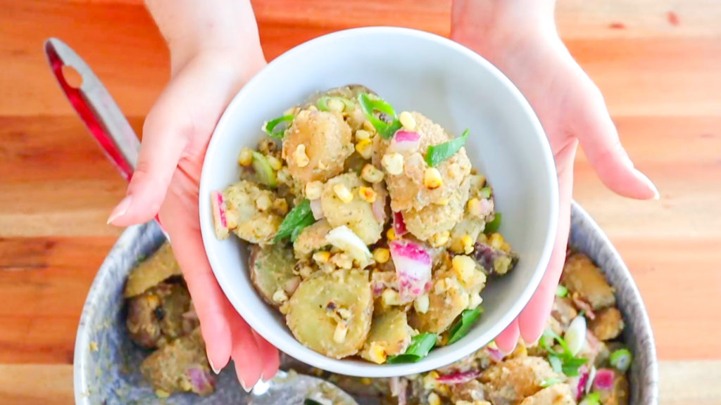 Hands holding a bowl of BBQ Ranch Potato Salad