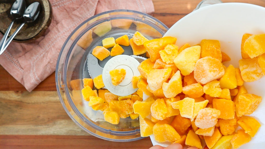 Chunks of frozen mango in a food processor