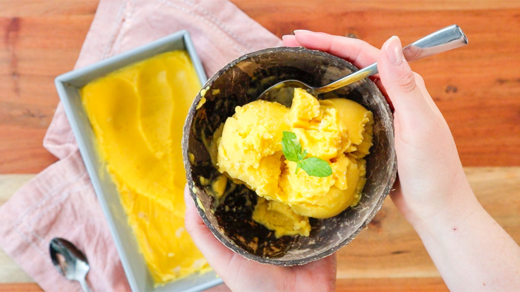 Hands holding a bowl of mango sorbet