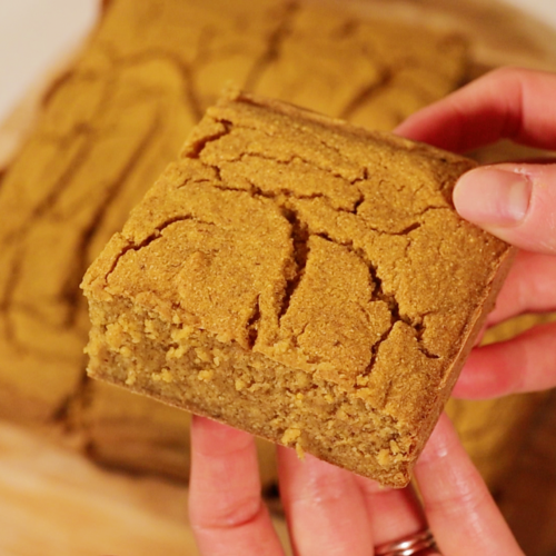 hand holding a square of pumpkin cornbread