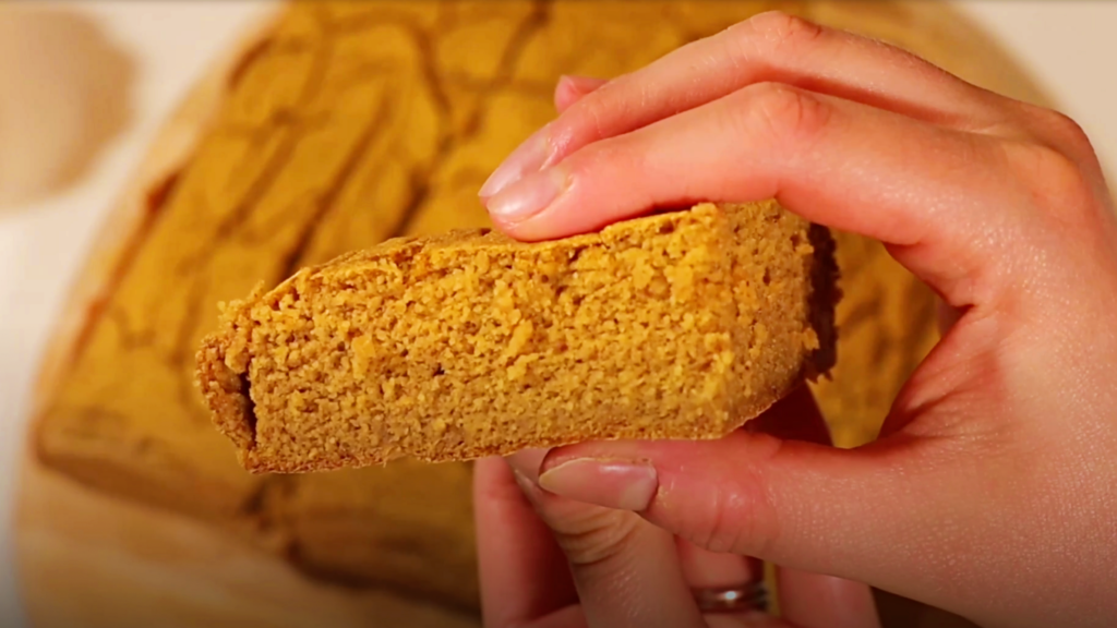 hand holding a square of sliced pumpkin conbread, showing the nice fluffy texture inside