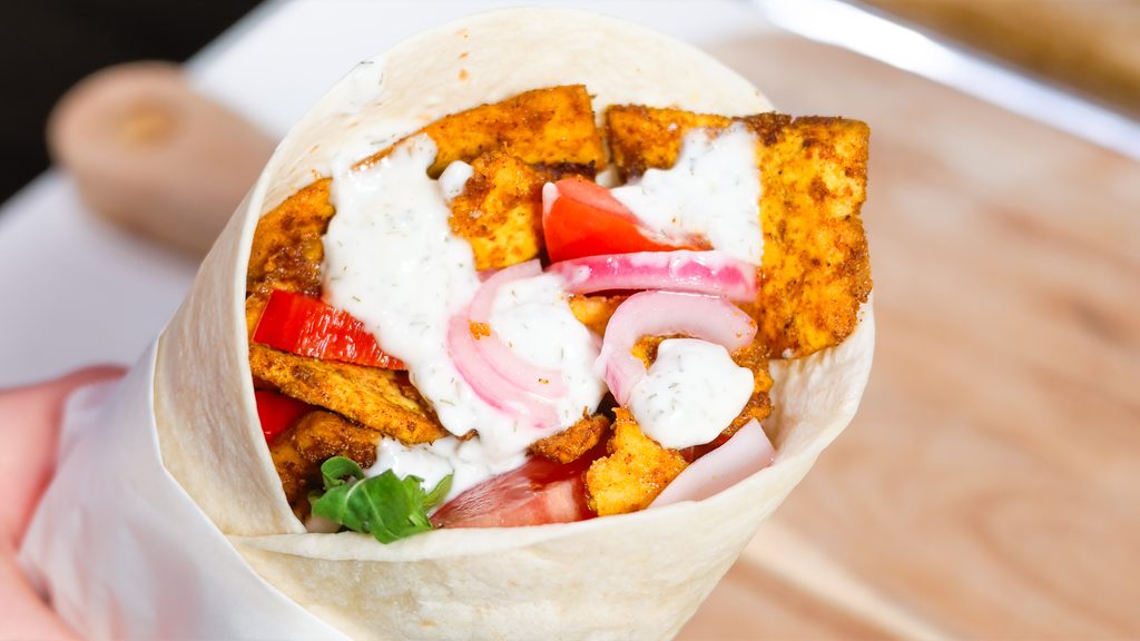 Hand holding a tofu shawarma wrap